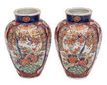 A pair of Japanese Imari vases of fluted baluster form painted with panels of flowers and foliage
