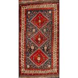 A Quashgai rug: the indigo field with triple red hooked lozenge medallions,