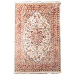 A Persian rug, machine made, with an ivory cartouche field, all over designs and main rust border,