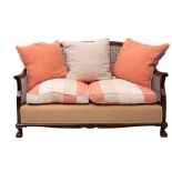 A mahogany and canework bergere sofa, early 20th century; with shallow arched back,