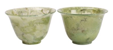 A pair of small Chinese jadeite wine cups the stone of celadon colour with cream and grey
