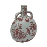 A Chinese porcelain moon flask painted front and verso in copper-red with a song bird amongst