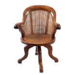 A Victorian walnut, birch and oak revolving office desk armchair with curved cane panel back,