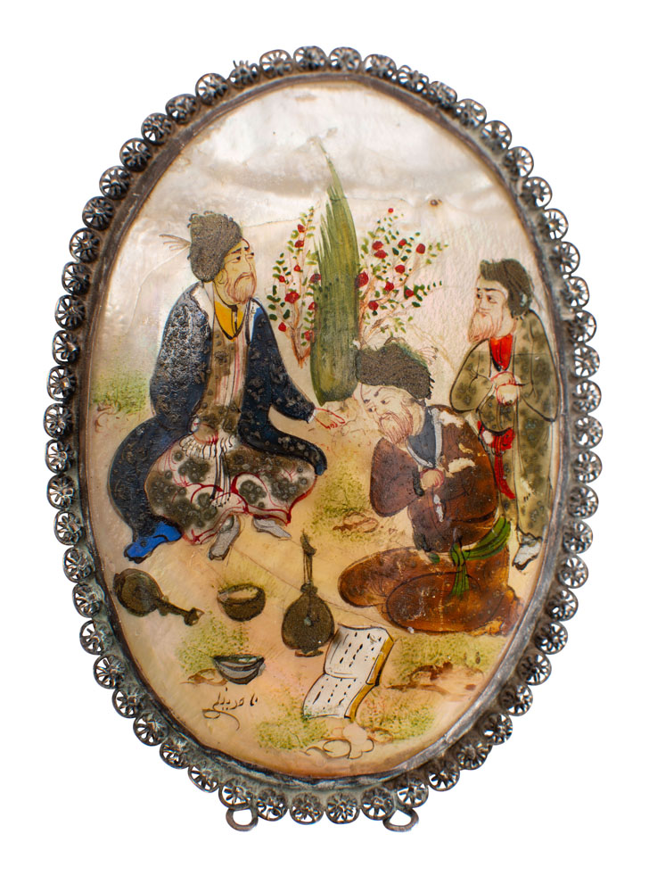 A Persian painted mother-of-pearl oval brooch decorated with three musicians in a garden setting,