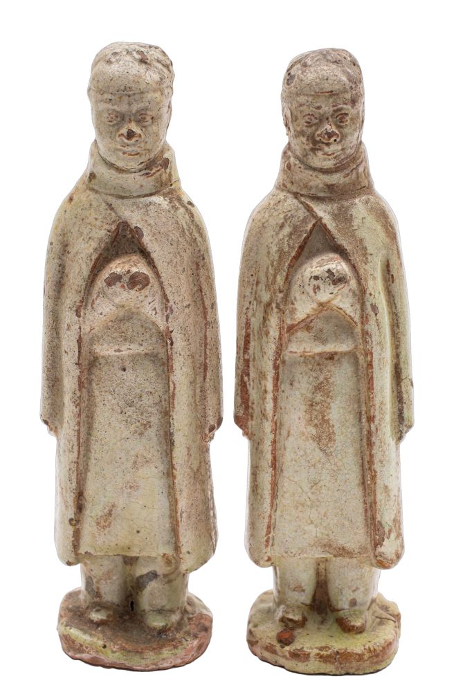 A pair of Chinese pale celadon glazed terracotta funerary figures each modelled standing with