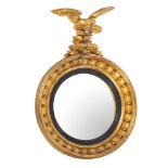 A Regency giltwood and gesso circular convex mirror surmounted by a figure of an eagle with