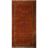 An Afghan rug the rust field with triple lozenge medallions and geometric designs,