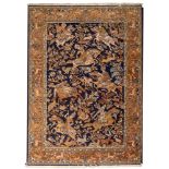 A Kashmiri rug, the indigo field with equestrian hunting figures and trees and flowers,