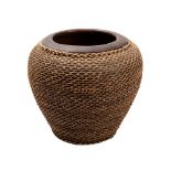 A large Balinese earthenware bowl clad in wicker work, 30cm high.