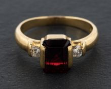 An 18ct gold octagonal step-cut garnet and round brilliant-cut diamond three-stone ring,