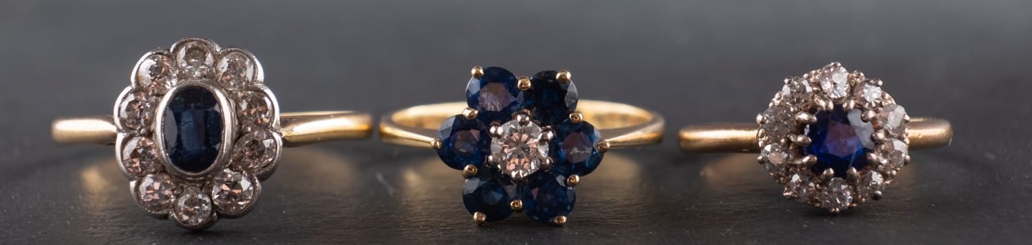 Three diamond and sapphire cluster rings, including an 18ct gold ring, with...