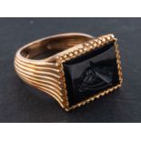 An black paste intaglio ring, depicting a horse's head, with reeded shoulders and mount,