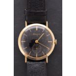 Bulova, a gentleman's 14K gold wristwatch the black dial having gold baton numerals and hands,