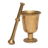 A brass mortar of chalice shape, on circular foot, 21cm high, together with a brass pestle.