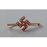 A yellow metal Swastika brooch inset with sea pearls and rubies, 2.1g.