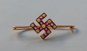 A yellow metal Swastika brooch inset with sea pearls and rubies, 2.1g.