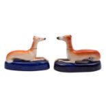 A pair of Staffordshire greyhound inkwells the recumbent dogs on cobalt blue bases,