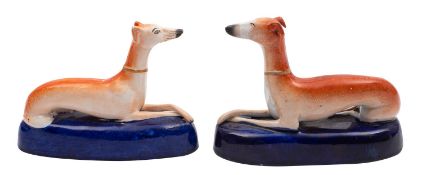 A pair of Staffordshire greyhound inkwells the recumbent dogs on cobalt blue bases,