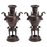 A pair of Japanese bronze two-handled vases cast in relief with ho-o birds and on tripod supports