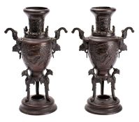 A pair of Japanese bronze two-handled vases cast in relief with ho-o birds and on tripod supports