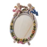 A German porcelain easel mirror in the Meissen manner applied with cherubs and flowers,