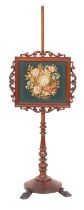 A Victorian mahogany pole screen; with an adjustable panel of needlework depicting a floral spray,