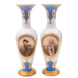 A pair of French opaline glass vases painted with pendant floral sprays and oval panels of young