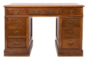 An Edwardian oak pedestal desk; the rectangular top with a moulded edge,