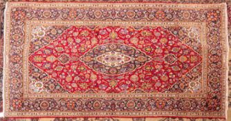 A Shadsar signed Kashan rug, the shaded wine cartouche field with a cartouche pendant medallion,