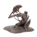 A Japanese bronze study of a hawk; perched on a gnarled tree stump, it's eyes picked out in gold,