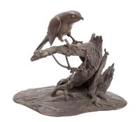 A Japanese bronze study of a hawk; perched on a gnarled tree stump, it's eyes picked out in gold,