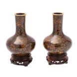 A pair of small Chinese cloisonné bottle vases decorated overall with flowers and foliage on a dark