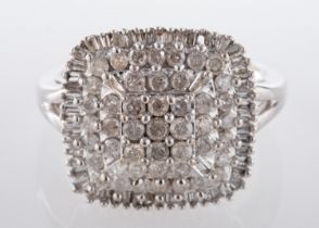 A diamond cluster ring, the cushion shaped plaque claw-set with circular and baguette cut diamonds,