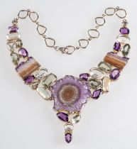 A multi gem set necklace, the central rough cut amethyst suspending vari cut amethysts and quartz,