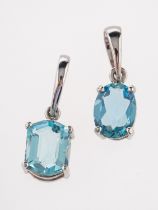 Two platinum aquamarine pendants, each oval shaped stone claw set with a plain bale loop.
