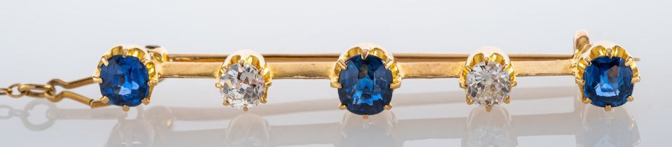 A sapphire and diamond bar brooch, set with alternating circular cut sapphires and old cut diamonds,
