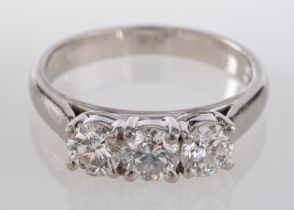 A platinum three stone diamond ring, claw set with brilliant cut stones the largest at the centre,