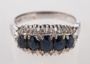 A sapphire and diamond ring, the central row of oval cut sapphires with eight diamonds to the edge,