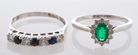 Two gemset rings, including an oval, mixed-cut emerald and diamond cluster ring, stamped '18K',