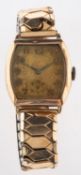 A Swiss gentleman's gold wristwatch the cushion dial with raised Arabic numerals and subsidiary