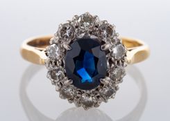 An 18ct gold, oval, mixed-cut sapphire and round, brilliant-cut diamond cluster ring, 1.