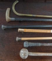 A 9ct gold mounted walking cane, two silver mounted walking canes, two walking sticks,