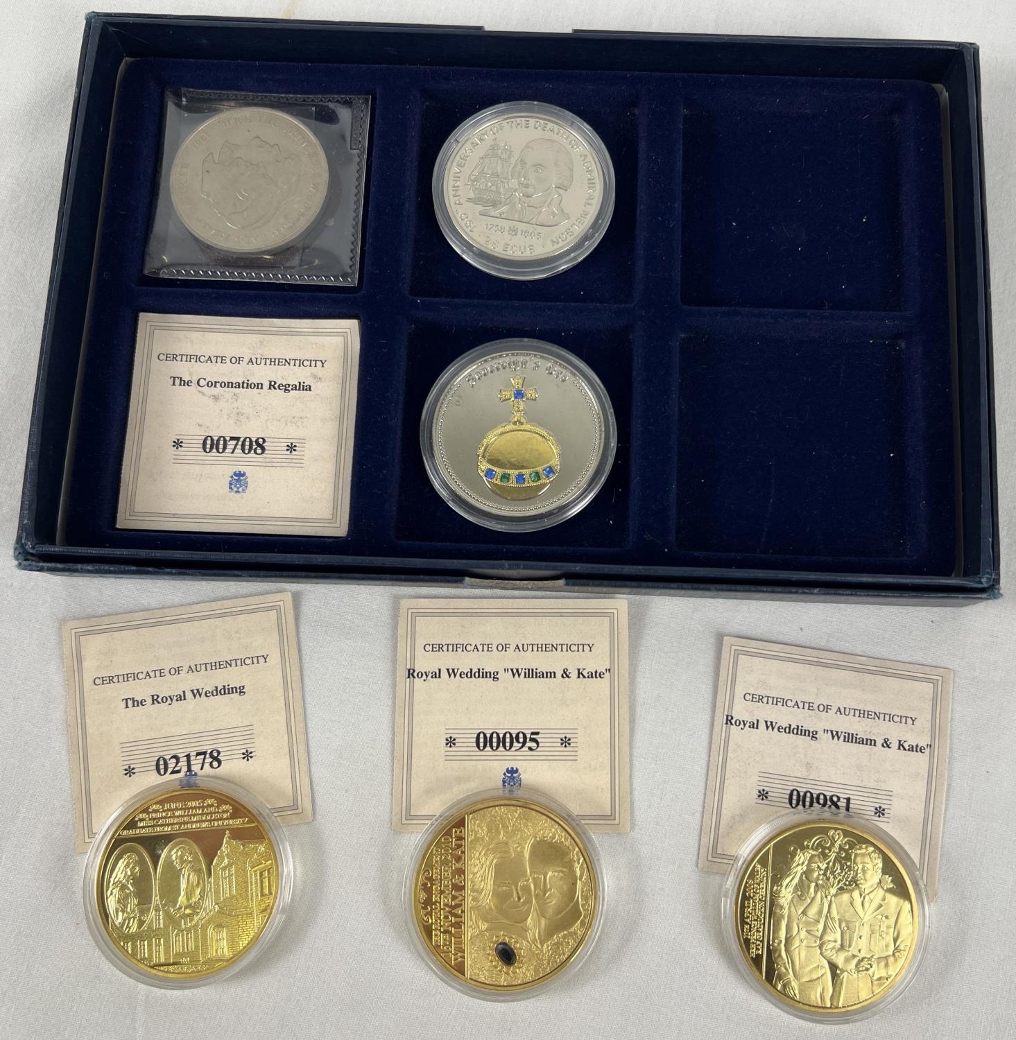 A presentation box containing a collection of commemorative crowns and proof coin/medallions. 3 gold