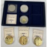 A presentation box containing a collection of commemorative crowns and proof coin/medallions. 3 gold