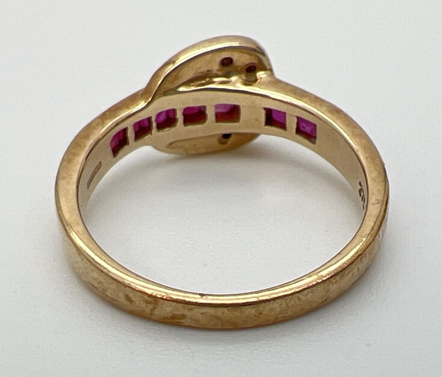 A 9ct gold ruby and diamond set buckle style dress ring. Band channel set with 5 square cut - Image 4 of 4