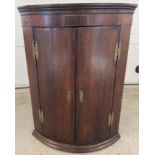 A large antique dark wood curved front corner cupboard with shell inlay decoration to top.