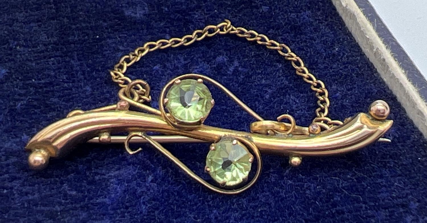 An Edwardian 9ct gold pin back brooch, set with 2 round cut pale green stones. Complete with