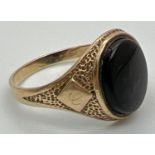 A mens 9ct gold vintage signet ring set with an oval black onyx stone. Pitted effect detail to