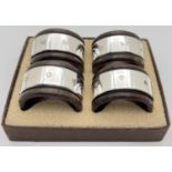 A boxed set of 4 dark wood napkin rings with hallmarked silver banded detail. Each approx. 4.5cm