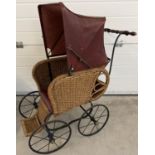 A large reproduction basket weave and leather dolls pushchair with black metal frame & wooden